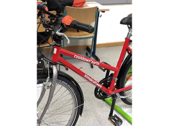 Ein rotes Fahrrad erzeugt durch Treten der Pedale Strom, der zB für den Betrieb eines Laptops genutzt werden kann
